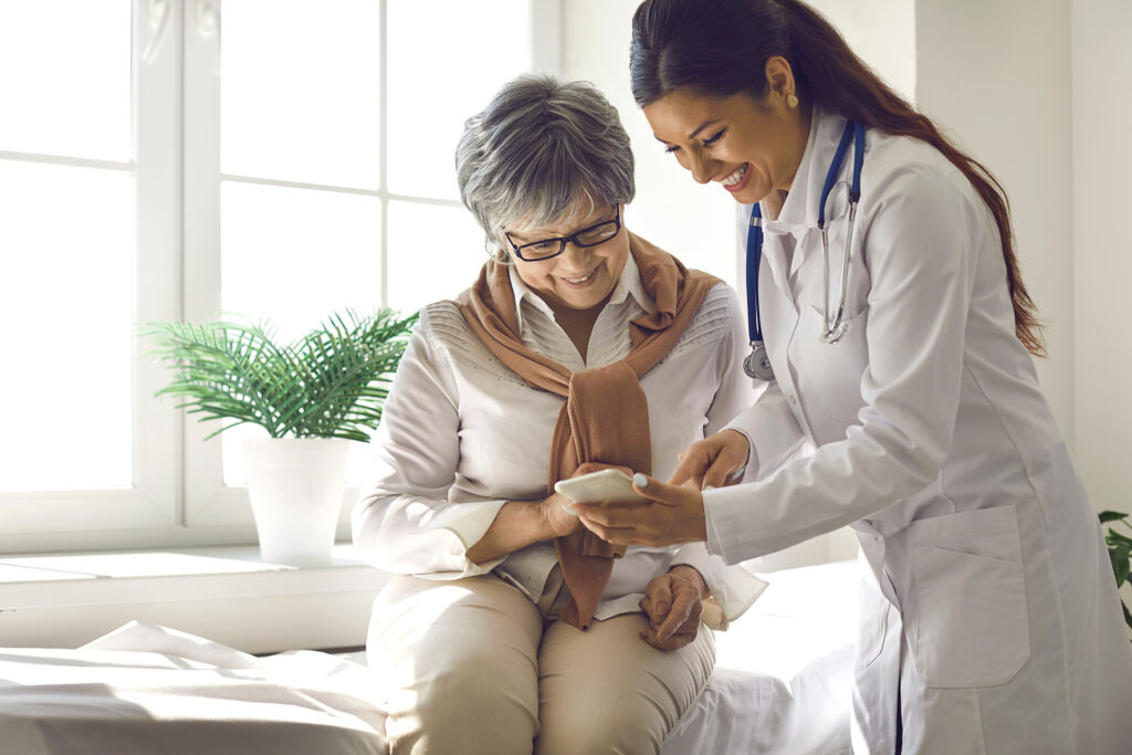 Caring doctor teaches female patient to use mobile healthcare app.